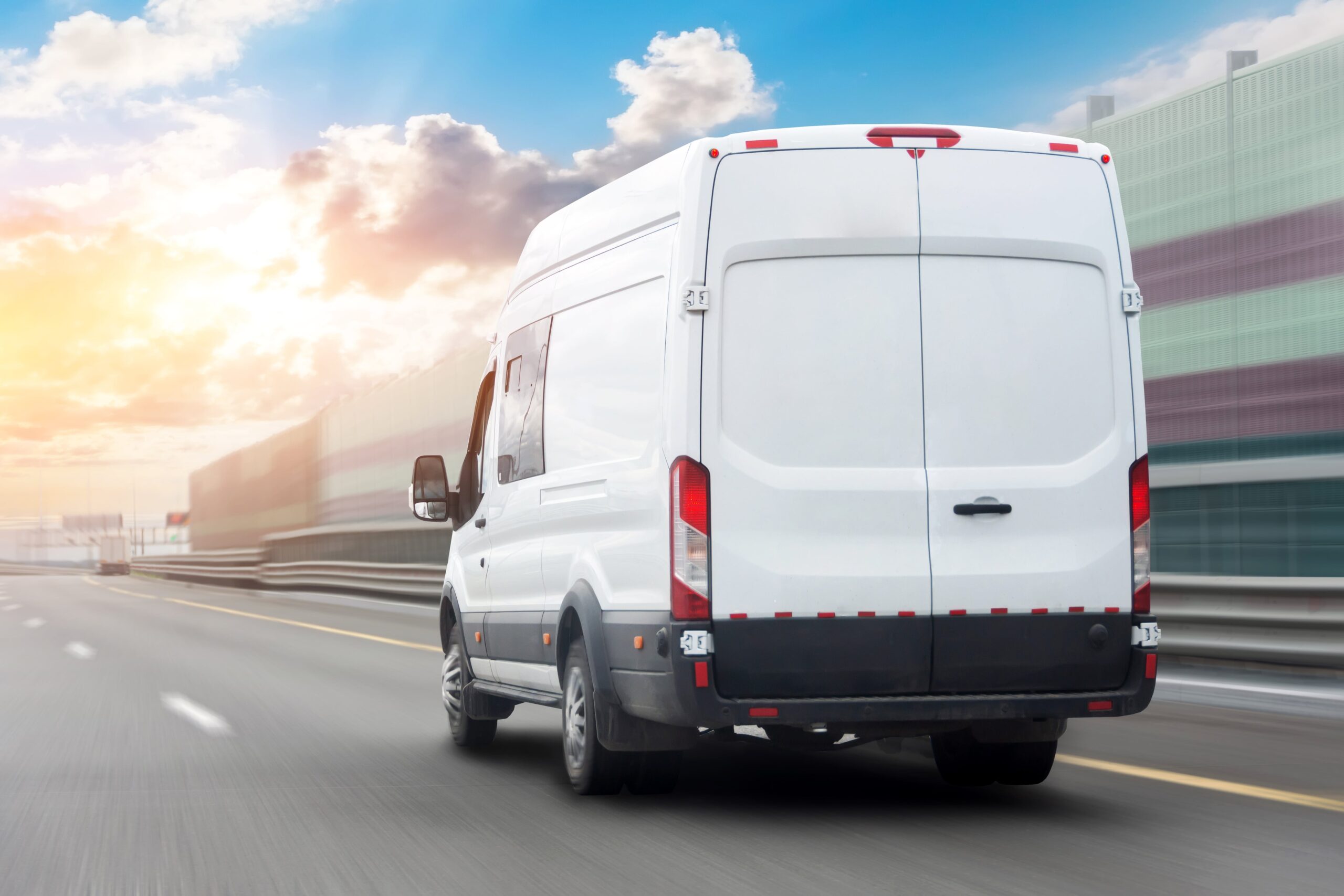 image of the back of a white delivery van traveling down a highway